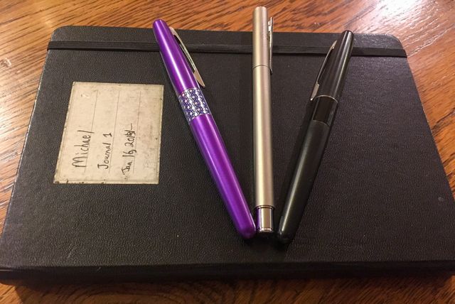 Three fountain pens on a notebook